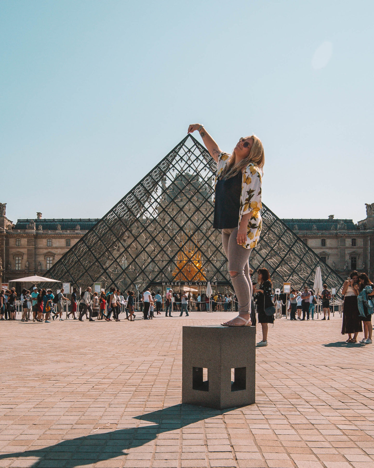 woman touching the top of the louvre pyramid in paris france