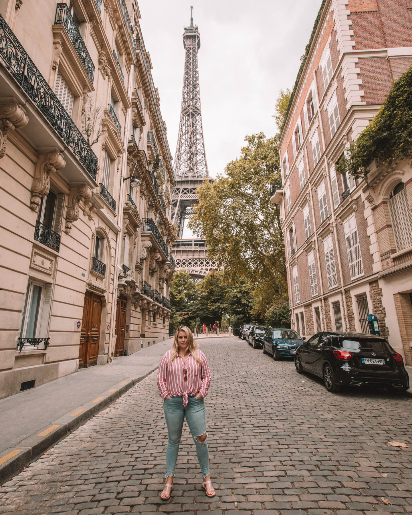 woman standing on cobblestone street in neighborhood overlooking the eiffel tower in paris france