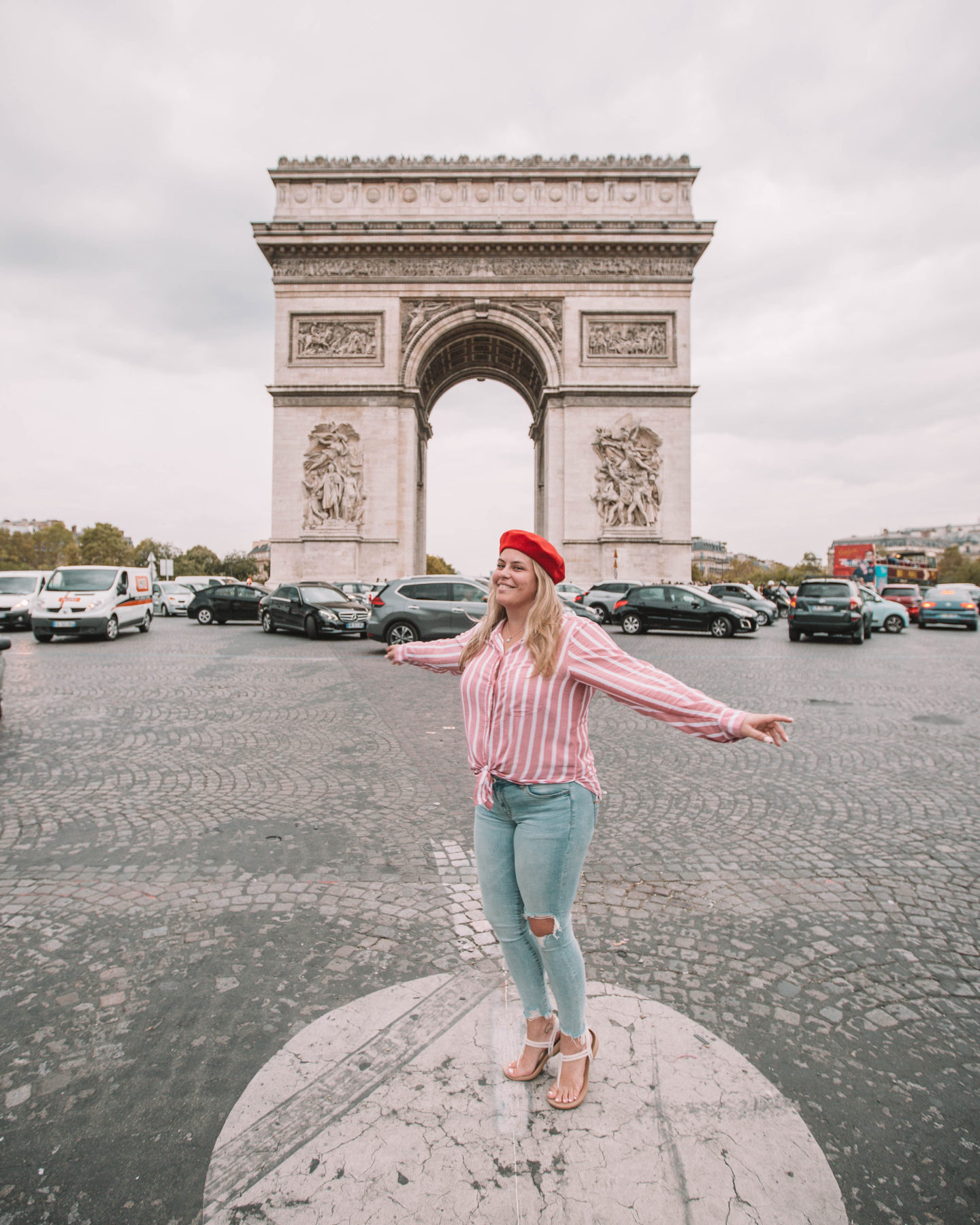 woman wearing red beret in front of the arc de triomphe in paris france