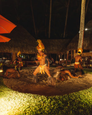 tahitian cultural dance with men in traditional costumes dancing for audience at dinner restaurant in bora bora