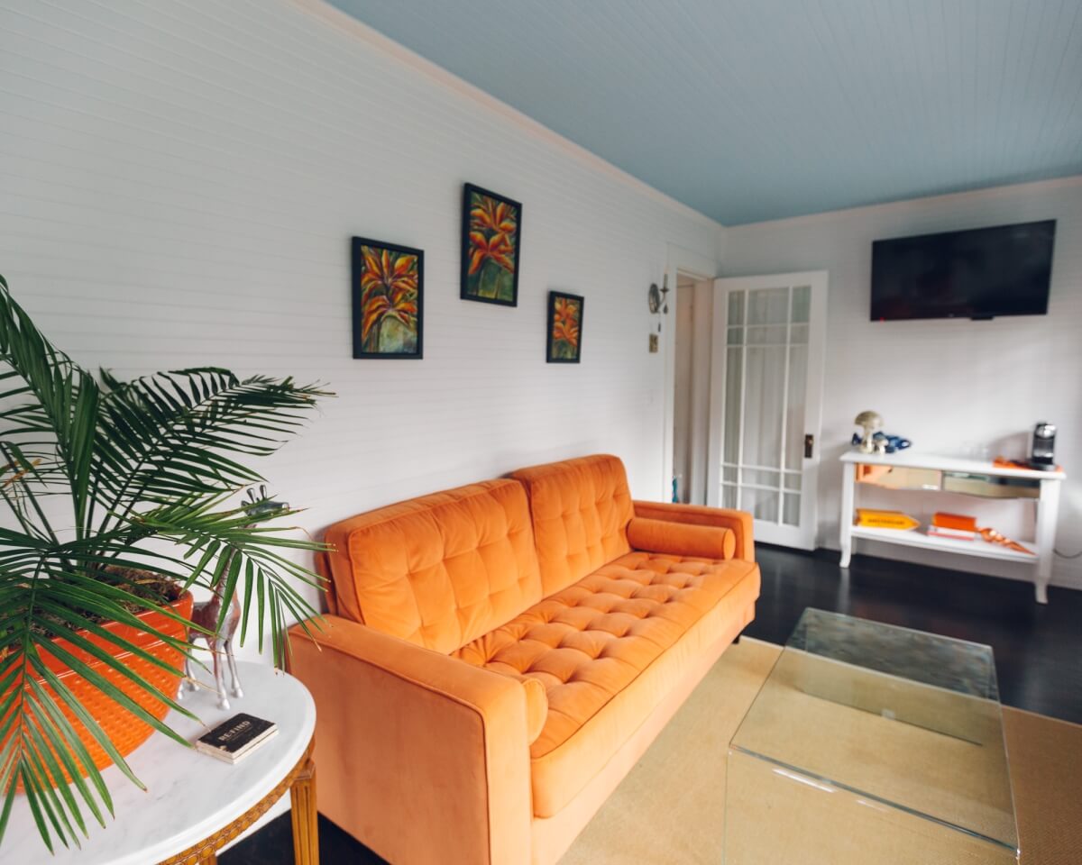 sitting room in suite at nobnocket boutique inn in vineyard haven martha's vineyard with bright orange couch and other accents