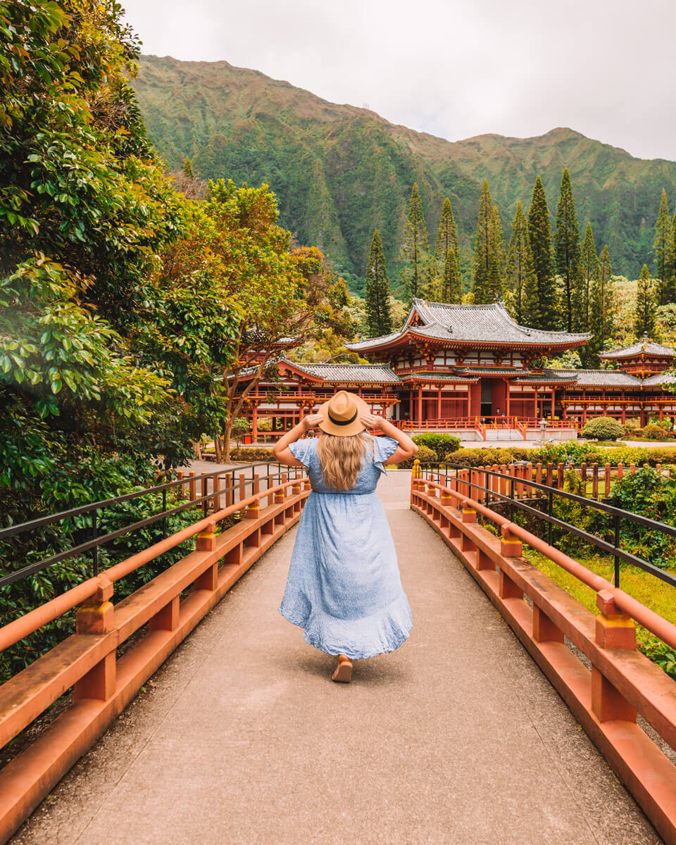 girl with blue dress and hat on at byodo in temple in oahu hawaii one of the things to do in oahu