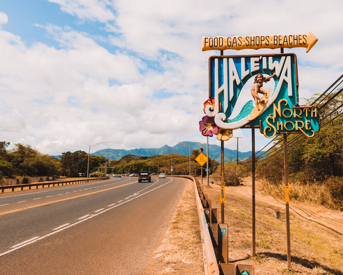 roadside sign for haleiwa north shore oahu hawaii with cars driving by