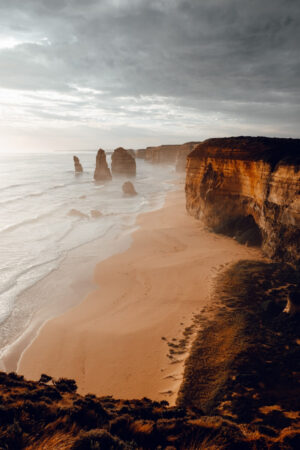 misty photo of the beach right before a storm at australia's twelve apostles outside of melbourne - the perfect spot for a honeymoon in december