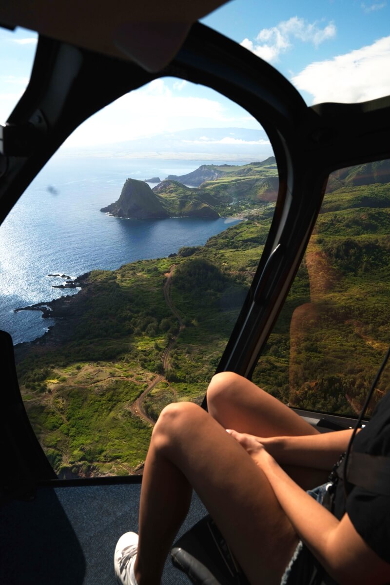 woman sitting against door in helicopter overlooking the coastline things to do in maui hawaii