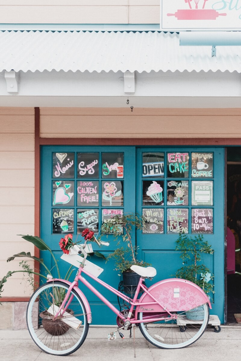 pink bike parked up against blue bakery door