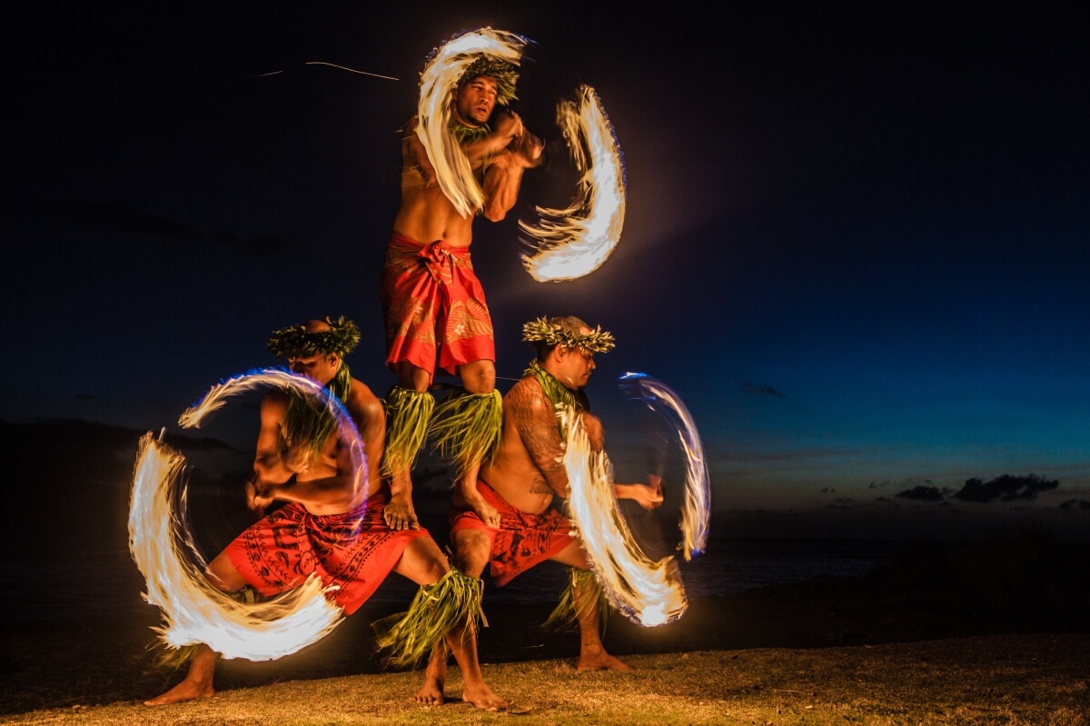 three men performing at a luau in maui hawaii with fire and traditional dress