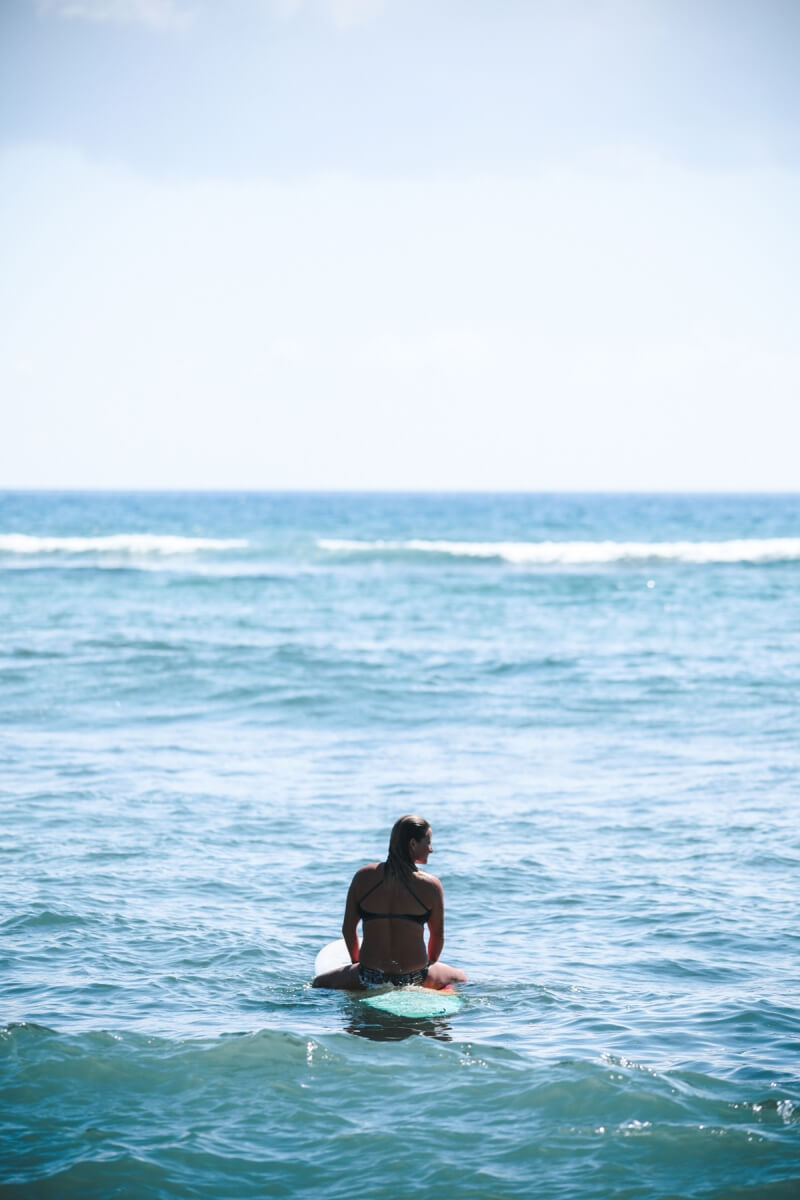 woman sitting up on surfboard in the water