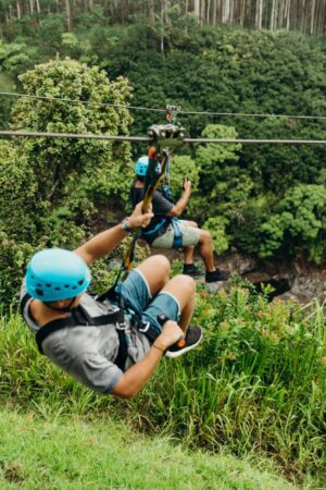 close up of two men zip lining through jungle