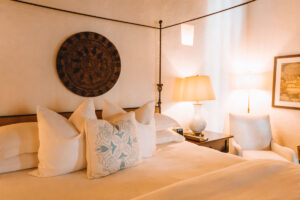 close up photo of white bed at hotel with light blue accent pillow and dark colored art on the wall