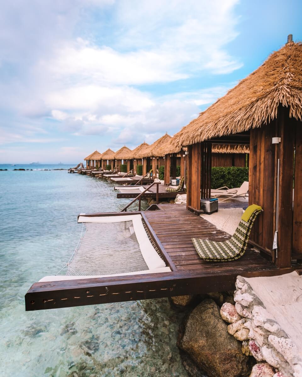exterior view of a row of private overwater beach cabanas on renaissance aruba private island