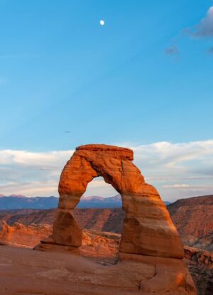 arch formation in arches national park in utah with blue skies and the moon
