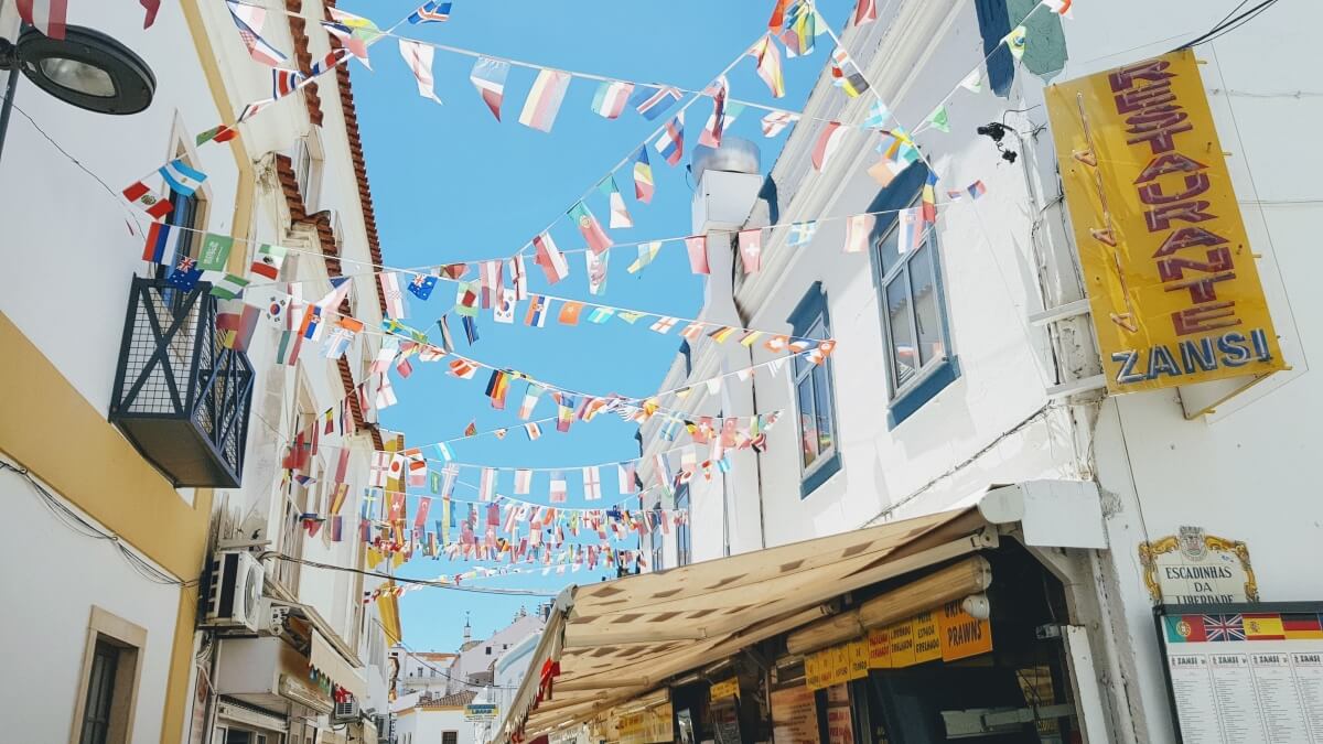 colorful flags lined across buildings in a street in albufeira portugal 