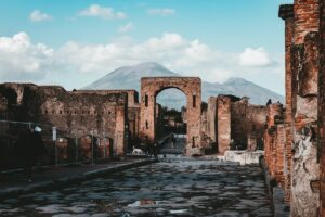 a view of the streets of the ancient city of Pompeii with an archway perfectly framing mt vesuvius in the background