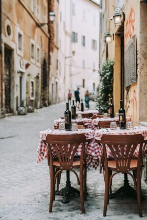 tables set with white and red checkered table cloths set with wine on the side of the road in rome italy