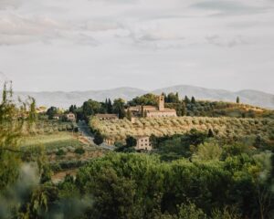 the rolling green hills in the tuscany countryside with an old tuscan building at the center