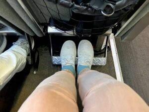 woman wearing white shoes and blueish green socks and tan pants with feet on footrest on alaska railroad train