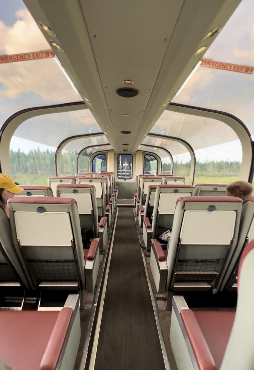 back of seats showing tray table and seat back pocket on alaska railroad's goldstar service with glass dome windows showing alaska wilderness
