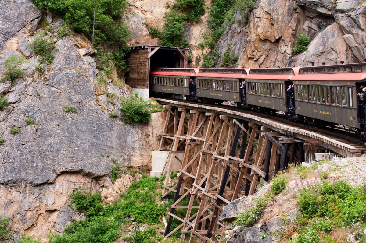 old railroad on wooden tracks goes through rock via tunnel