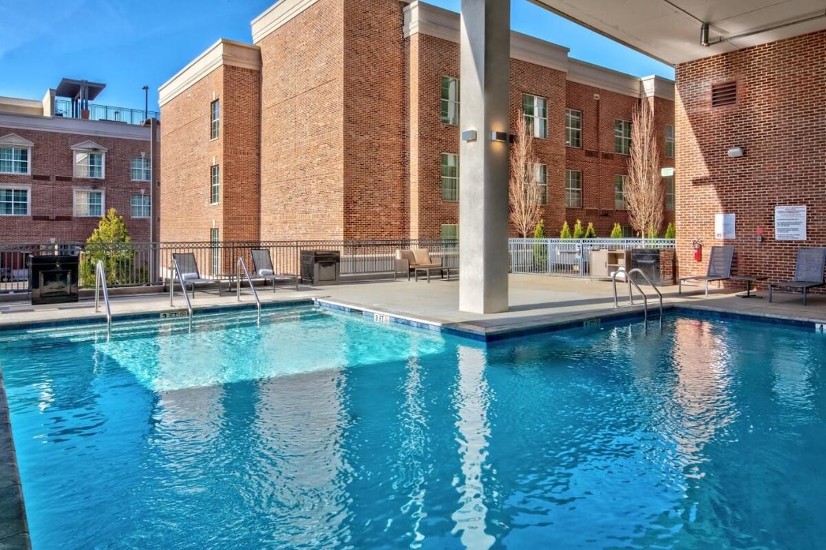a covered pool at the Residence Inn in Green Hills, Nashville with a few scattered pool chairs in front of a brick building
