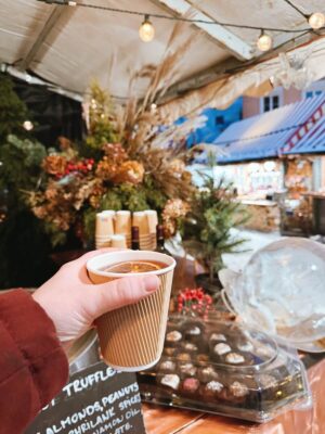 woman holding paper cup of hot mulled wine at Christmas Market in Riga, Latvia