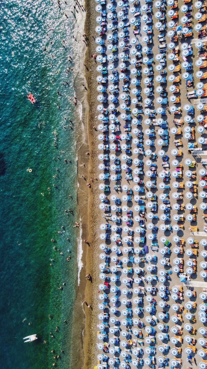 aerial view of a beach in Positano Italy with lots of umbrellas and chairs set up next to the shoreline